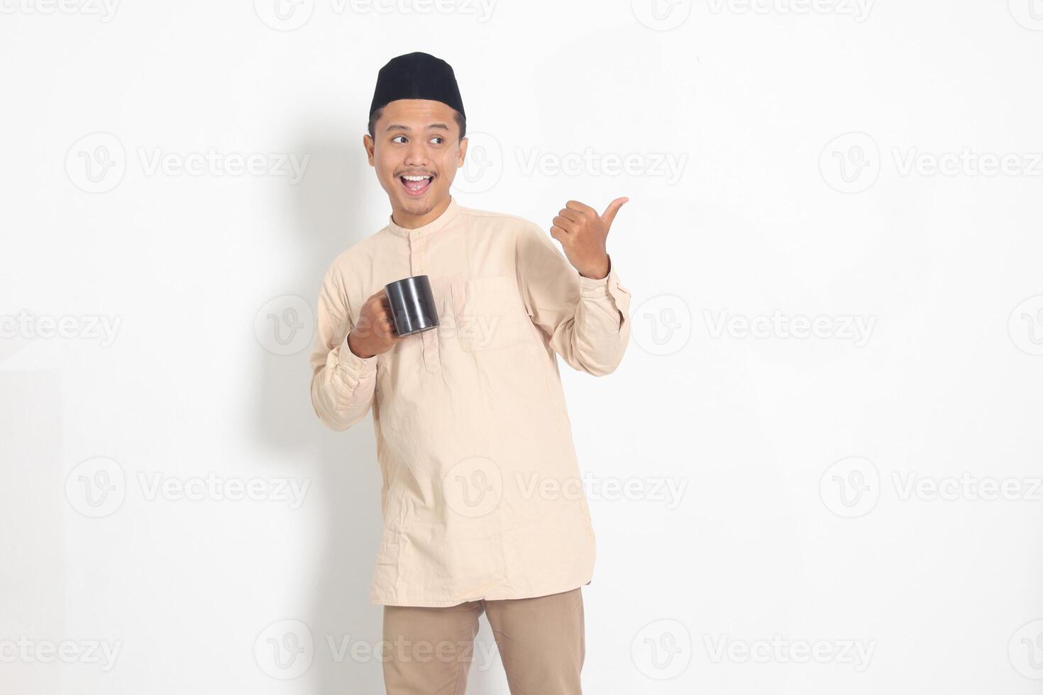 retrato de atractivo asiático musulmán hombre en koko camisa con peci participación un taza, Bebiendo agua, temple sed después ayuno. aislado imagen en blanco antecedentes foto