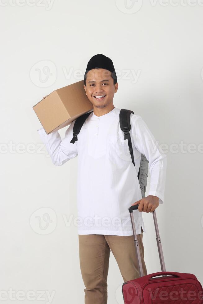 Portrait of attractive Asian muslim man carrying cardboard box and suitcase and standing with confident. Going home for Eid Mubarak. Isolated image on white background photo