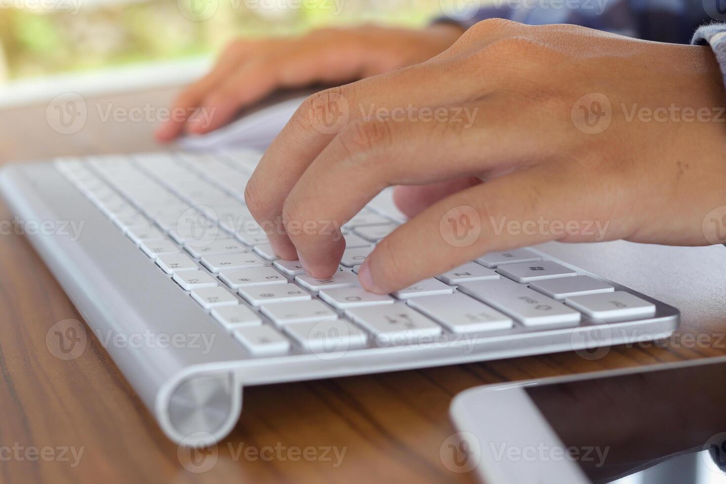 Close up of male hand using wireless keyboard and mouse in office desk. Casual working concept photo