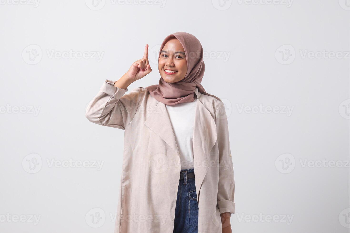 retrato de emocionado asiático hijab mujer en casual traje señalando arriba su dedo índice y recordando alguna cosa a hacer. mujer de negocios concepto. aislado imagen en blanco antecedentes foto