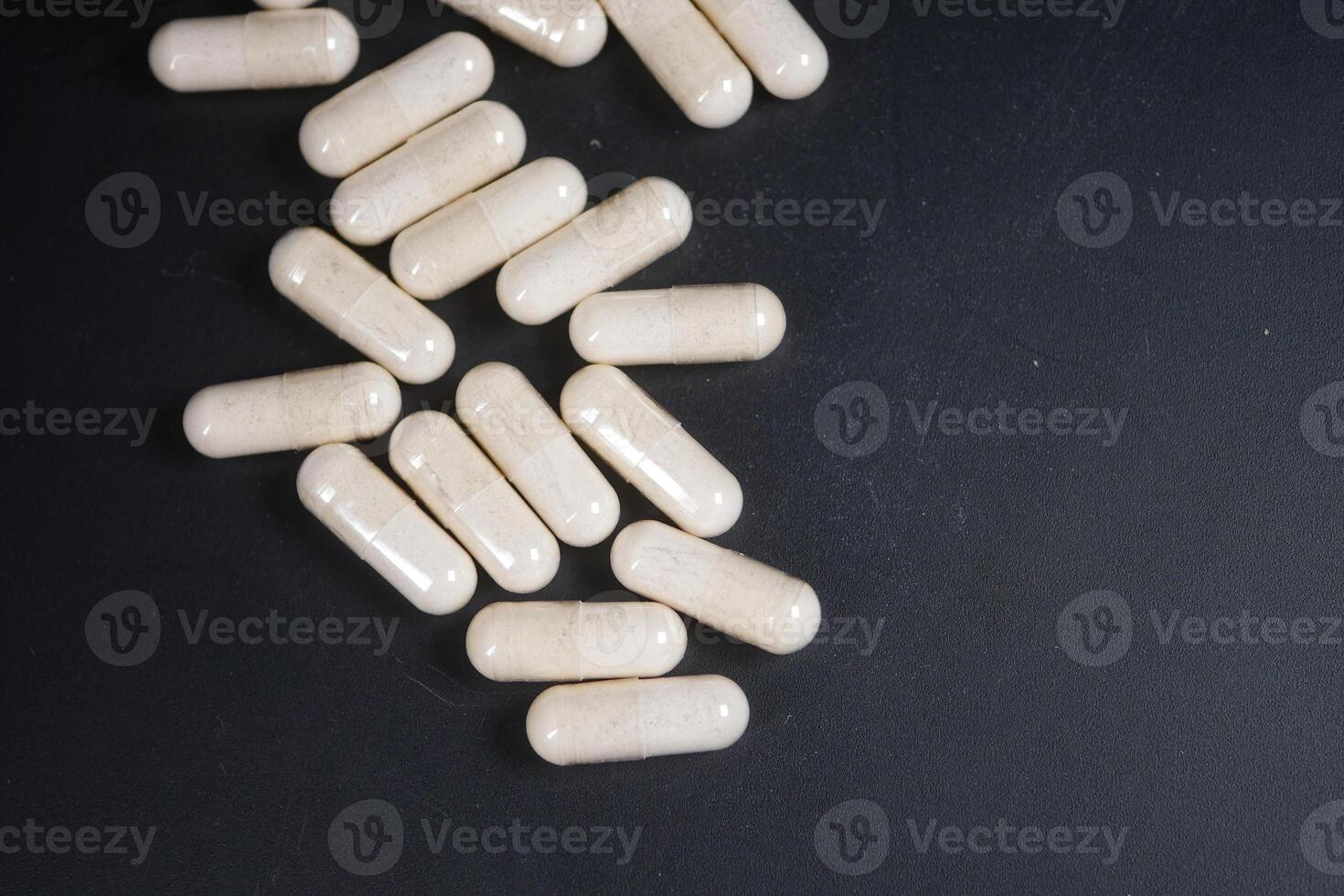 top view of herbal medicine capsule dropping on black background photo