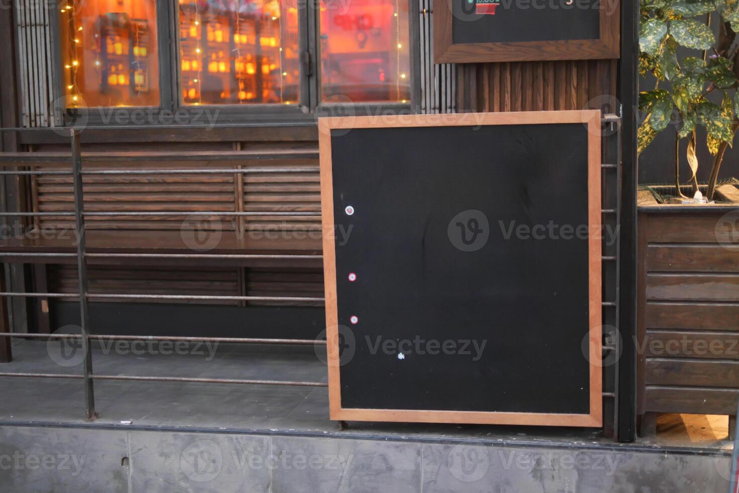 Empty wooden blackboard mockup standing outdoors in front of cafe photo