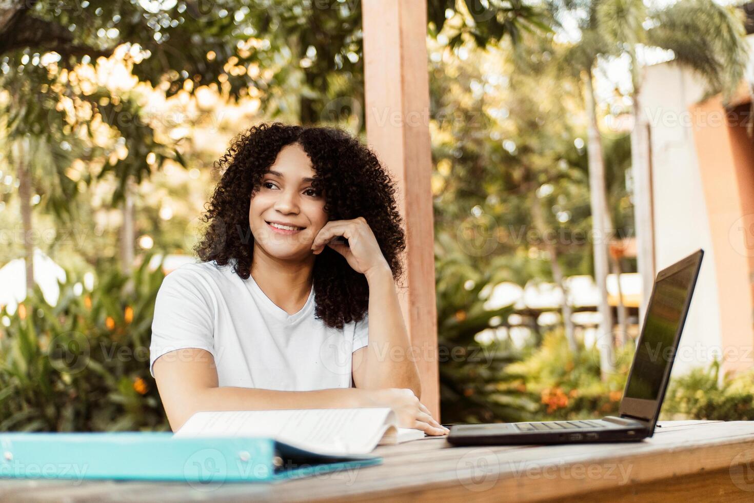 Happy student smiling posing sitting on a chair in a desk in a campus. photo