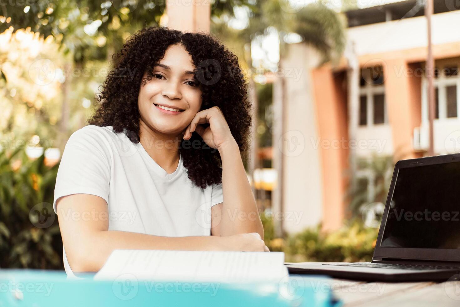 Happy student smiling posing looking at camera sitting on a chair in a desk at home photo