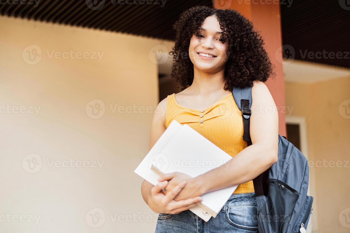 Smiling portrait of a young student with a backpack and holding some books. photo