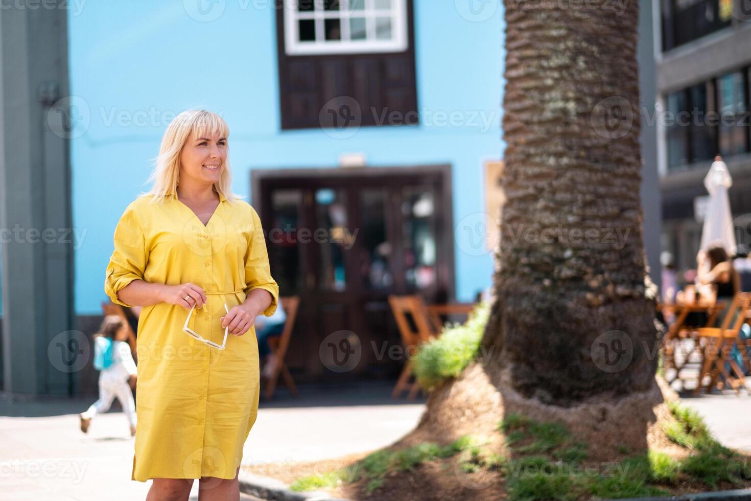 a blonde woman in a yellow summer dress stands on the street of the Old town of La Laguna on the island of Tenerife.Spain, Canary Islands photo