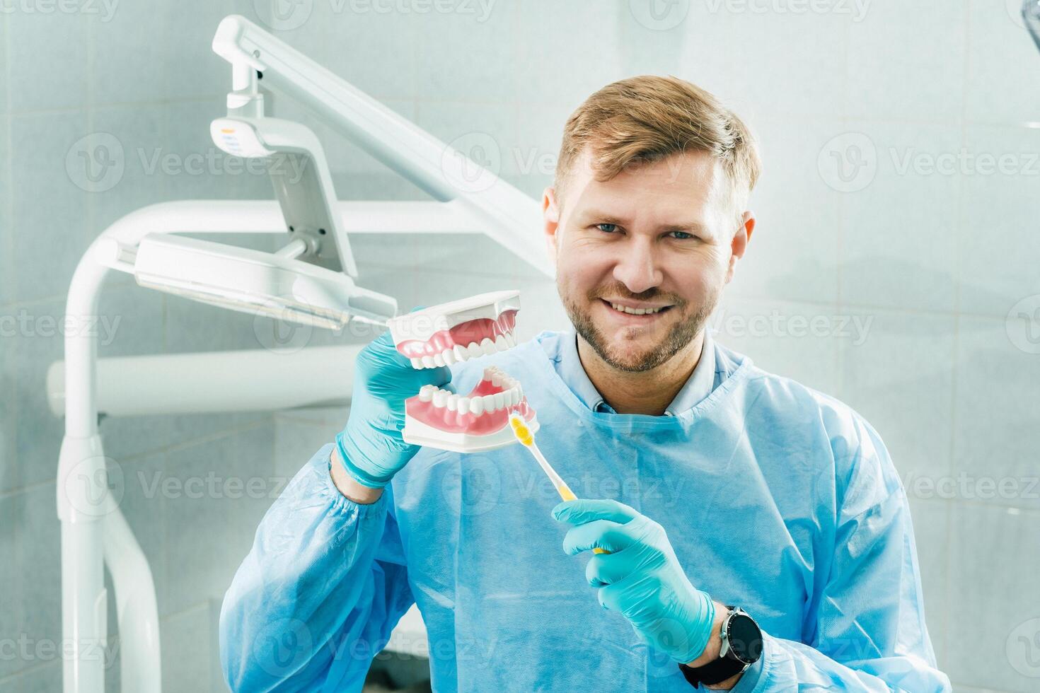 A model of a human jaw with teeth and a toothbrush in the dentist's hand photo