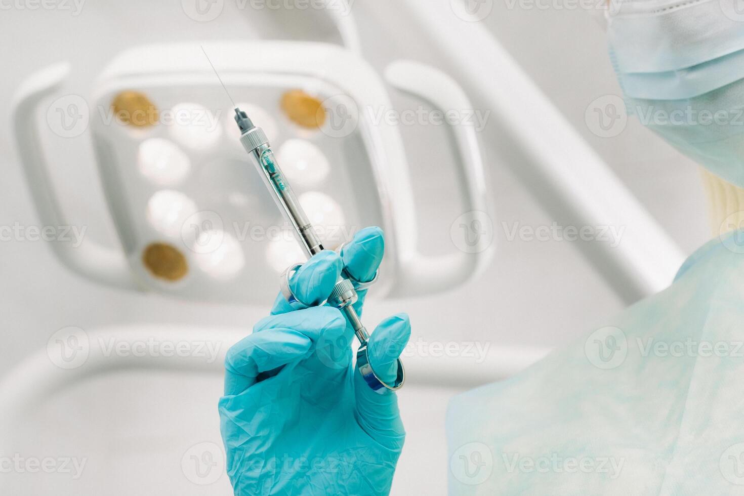 close-up of a dentist's hand holding an injection syringe for a patient in the office photo