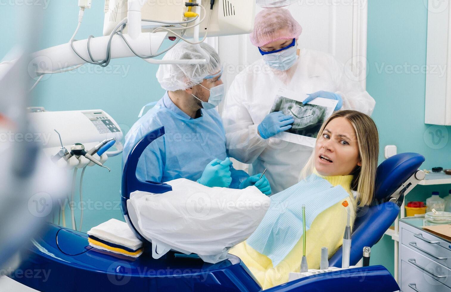 The dentist explains the details of the X-ray to his colleague, the patient is surprised by what is happening photo