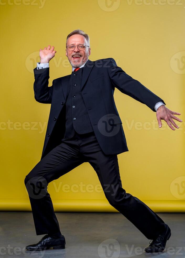 Senior manager man dancing at funny pose with expression. Yellow background. photo