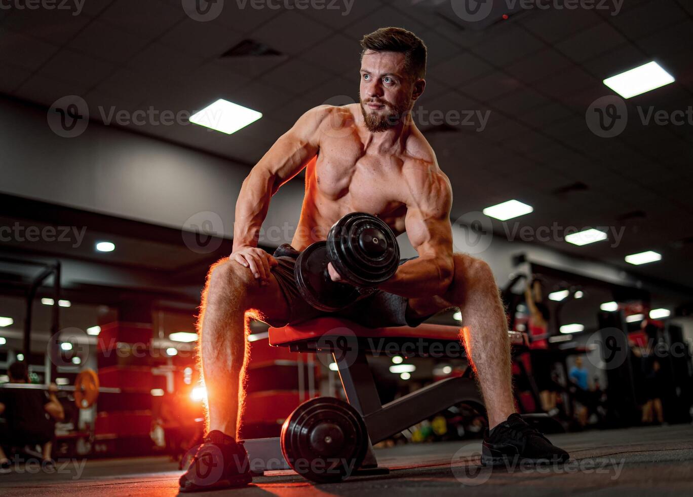 Young topless muscular man working out. Strong bodybuilder doing exercise in gym. photo