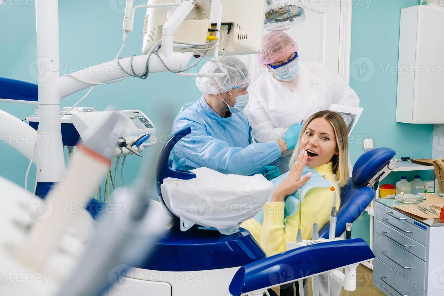 The dentist shows the details of the X-ray to his colleague, the patient is surprised by what is happening photo