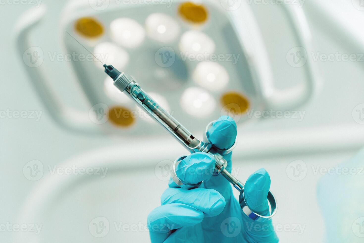 close-up of a dentist's hand holding an injection syringe for a patient in the office photo