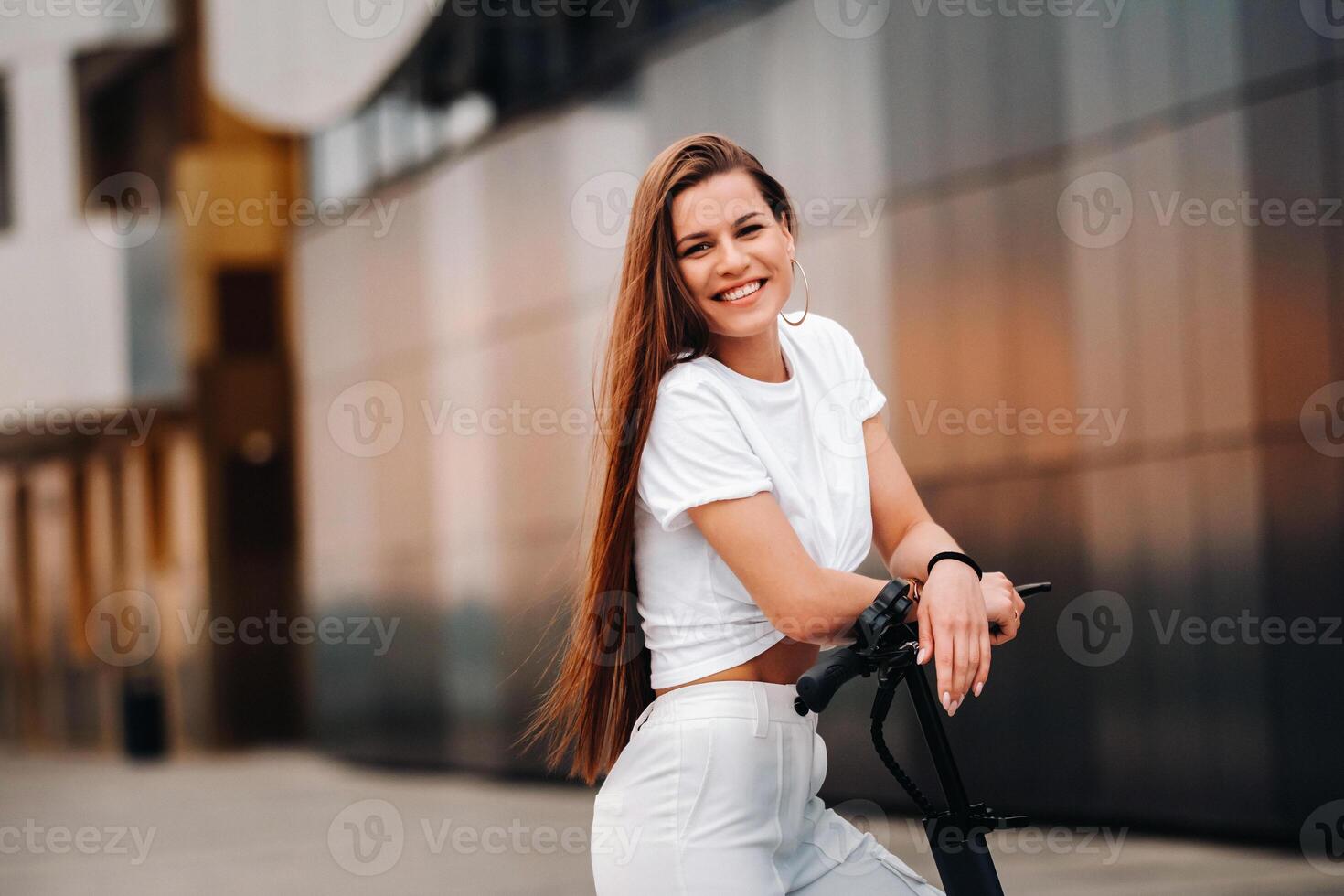 beautiful girl in white stylish clothes on an electric scooter in the city photo