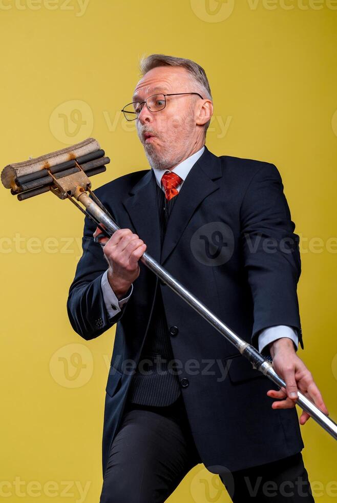 Adult man singing in mop. Holding broom like microphone. Man in suit. photo