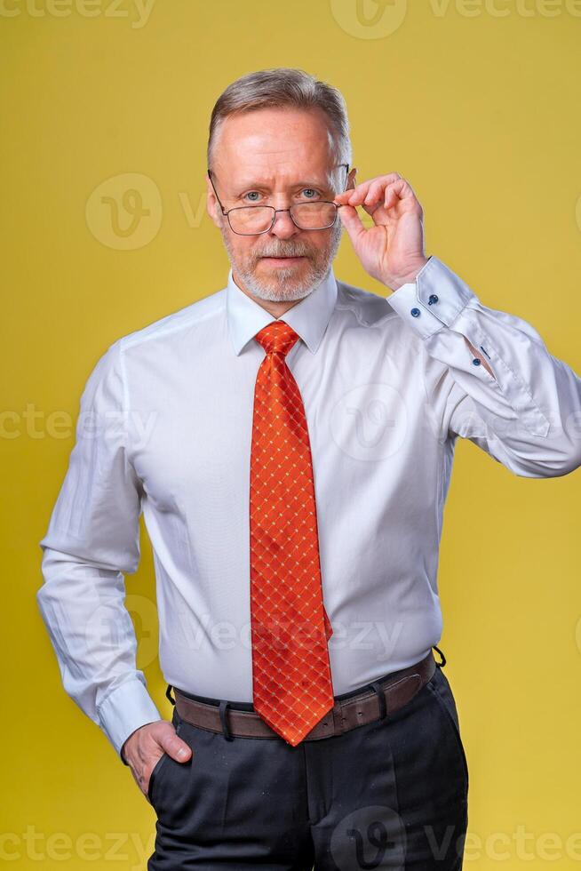 Portrait of a senior man in glasses. Man looking at camera. Business man in studio, yellow backgroung. Man in glasses portrait photo