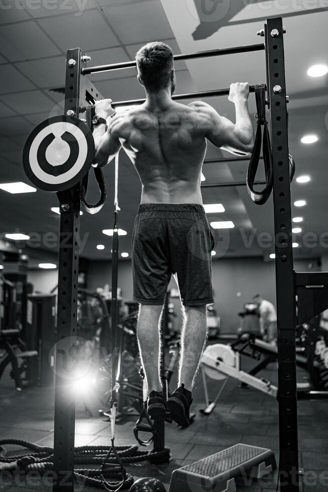 muscular fuerte hombre tracción arriba. poderoso joven ajuste masculino formación su atrás. foto