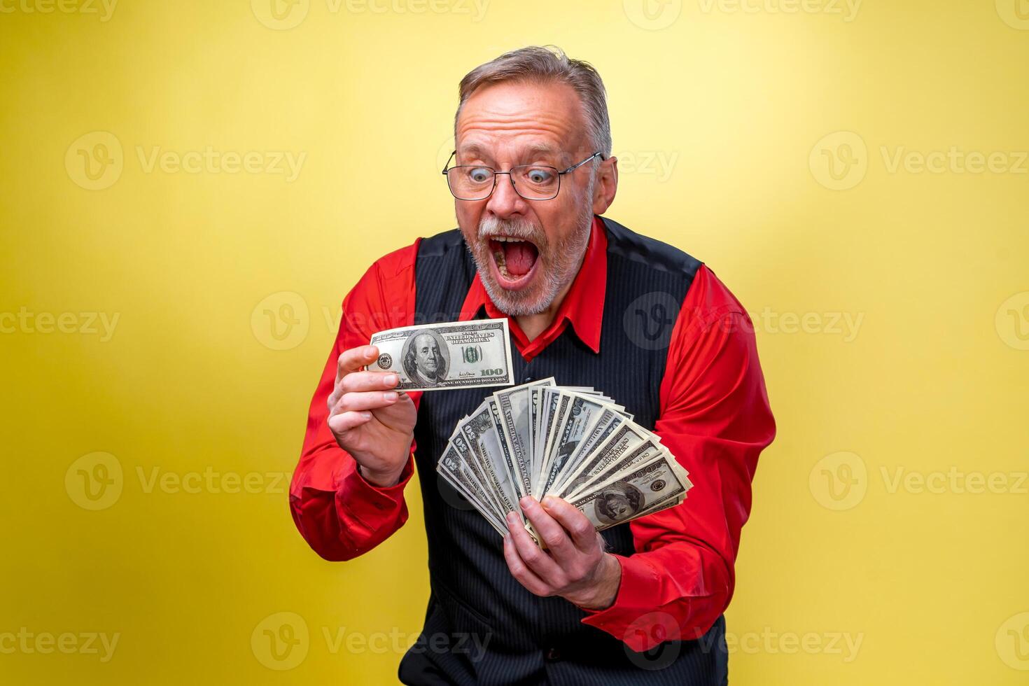 retrato de contento y blanco dientes sonrisa mayor antiguo empresario. hombre participación dinero en manos. vestido en rojo camisa, aislado en amarillo antecedentes. humano emociones y facial expresiones foto