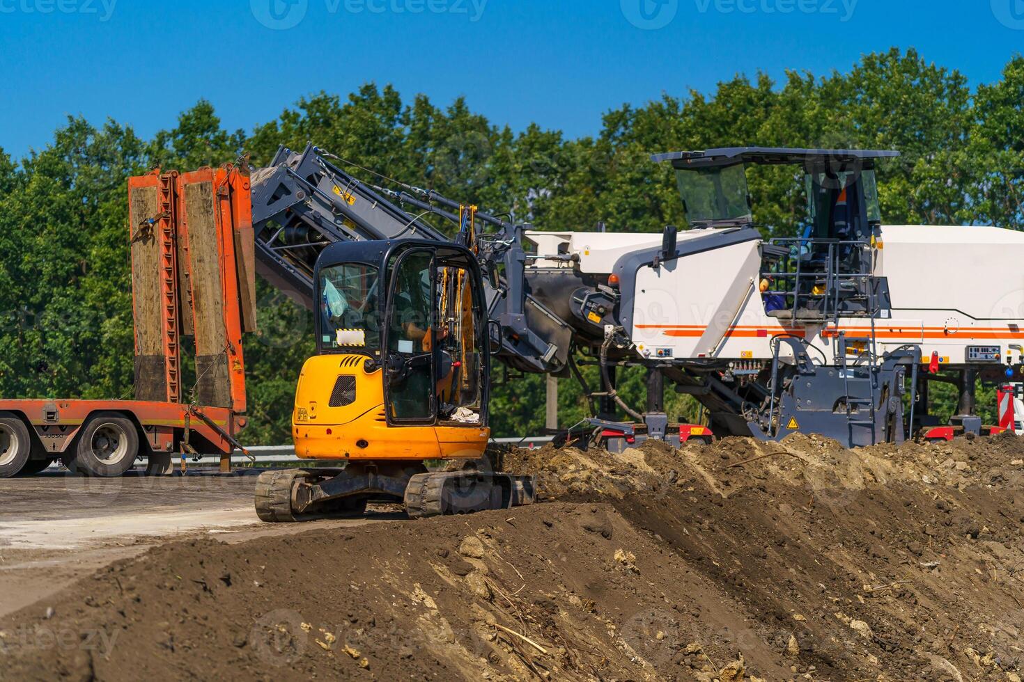 Yellow excavator on a construction site against blue sky.Aerial view. photo