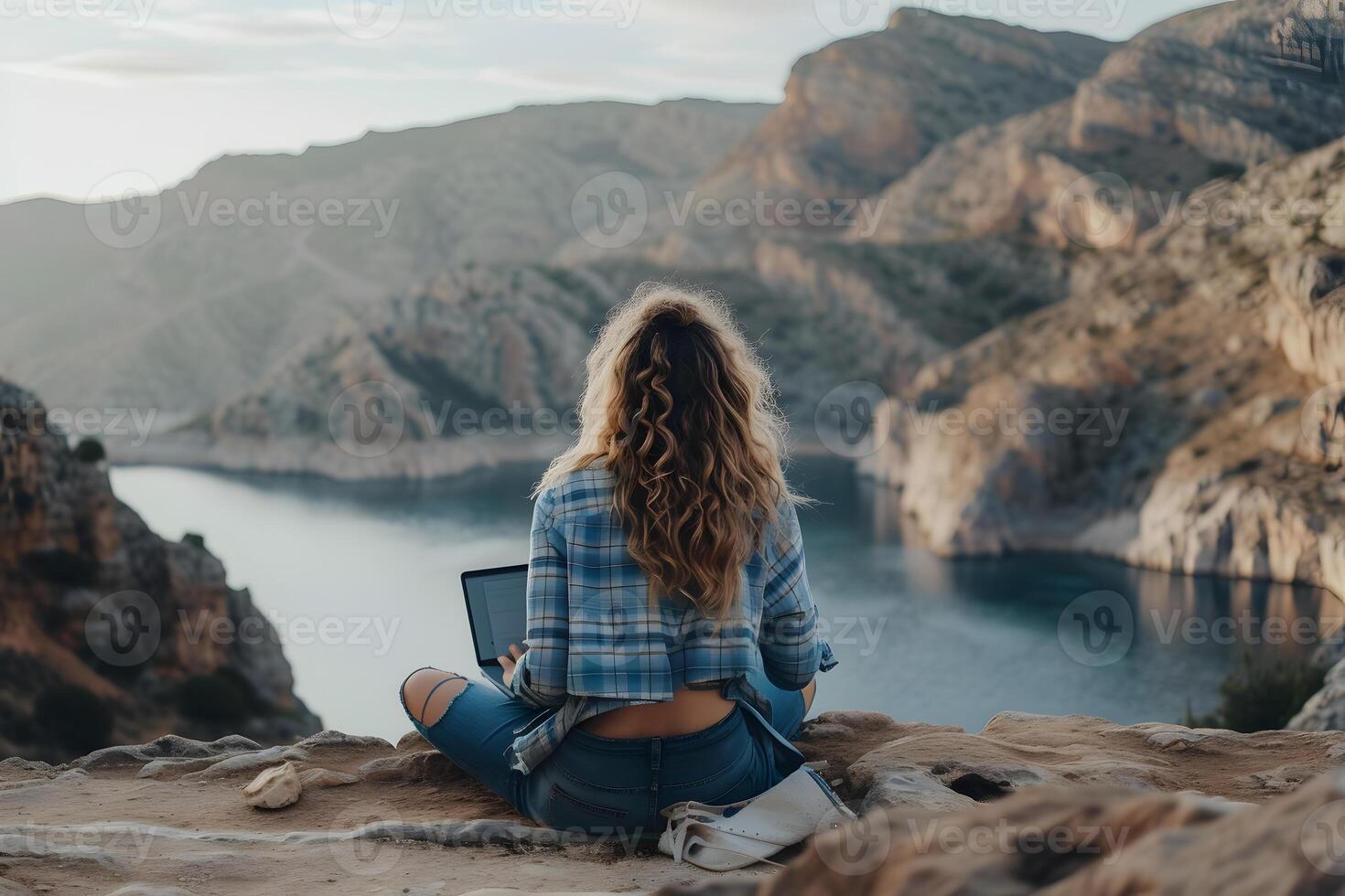 AI generated A woman sits on a rocky outcrop by the sea, her enjoys the beauty of nature while working remotely photo