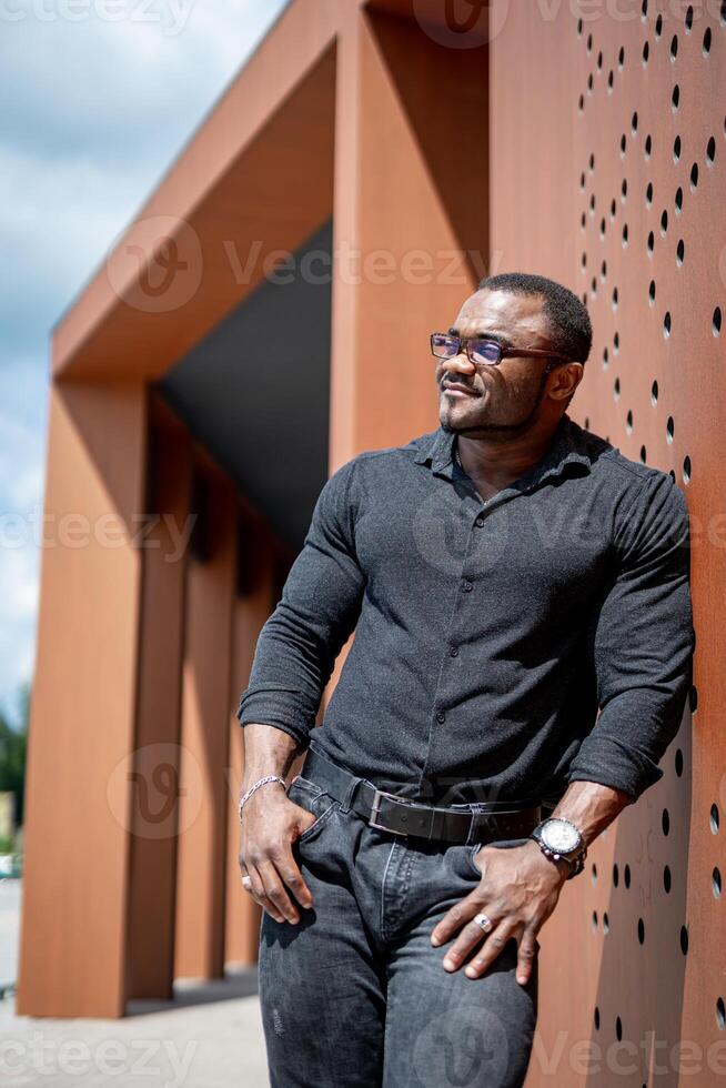 Stylish man in black shirt walking out the urban street. Handsome young model in elegant cloth. photo