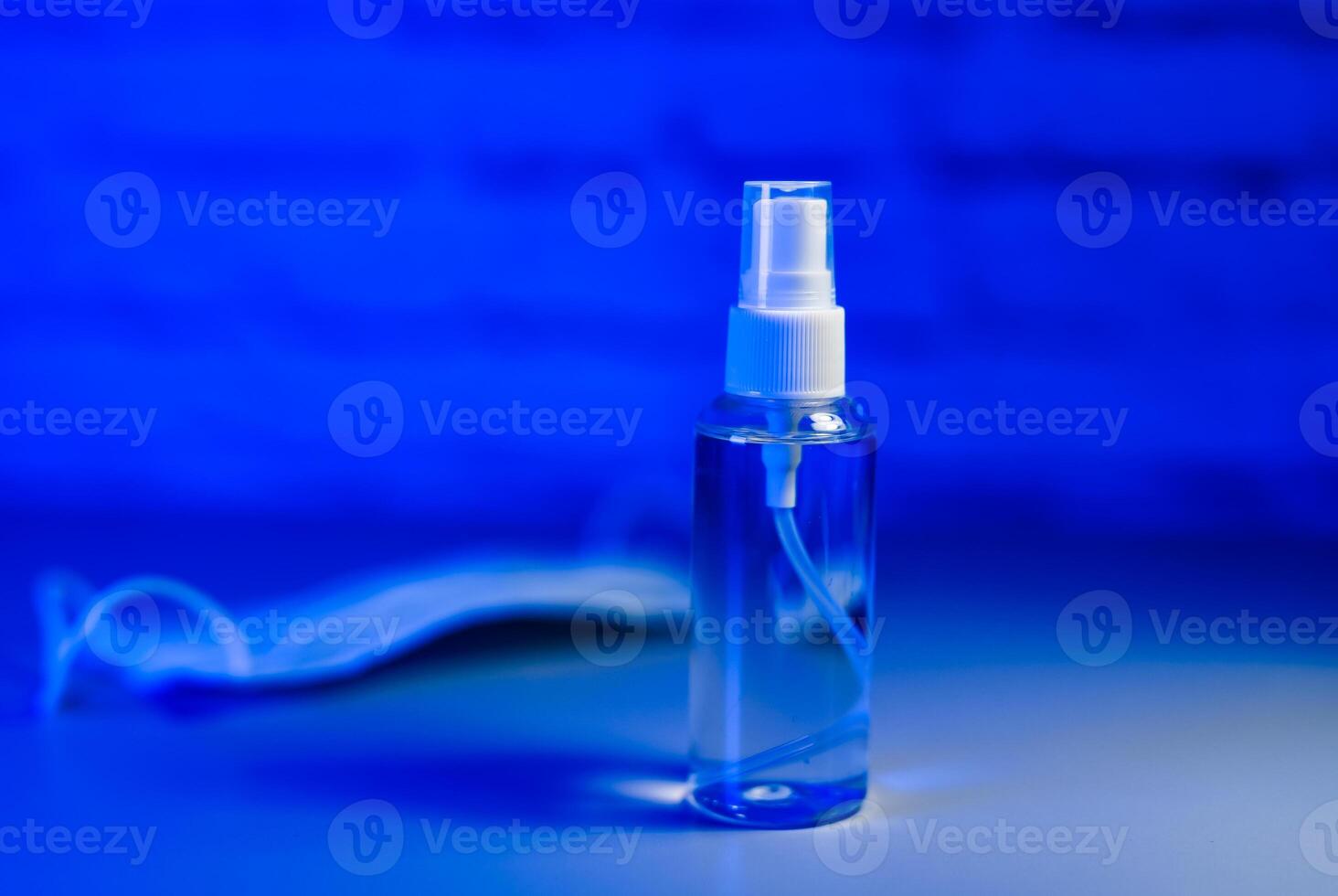 Medical mask and sanitizer on a blue background. Antiseptic and protective disposable mask on a blue background. Hygiene concept. Prevent spread of germs and bacteria and avoid infections coronavirus photo