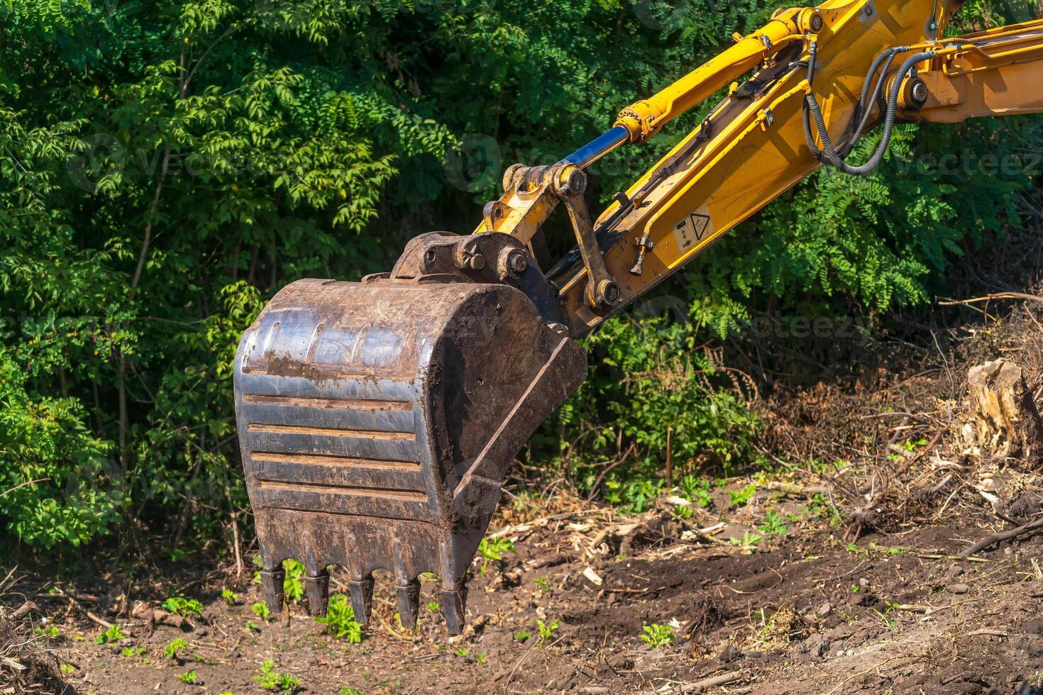 Yellow excavator on a construction site against blue sky. The arm of the excavator. Closeup photo