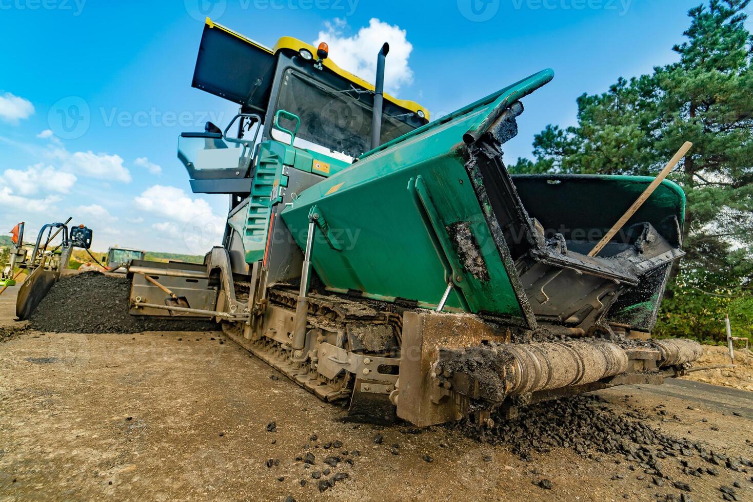 Road repair, compactor lays asphalt. Heavy special machines. Asphalt paver in operation. Side view. Closeup. photo