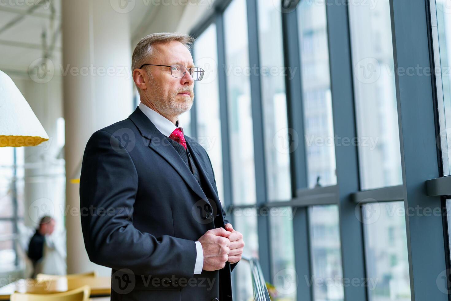 Businessman wears neatly white shirt and standing near big window with city view looking away. photo