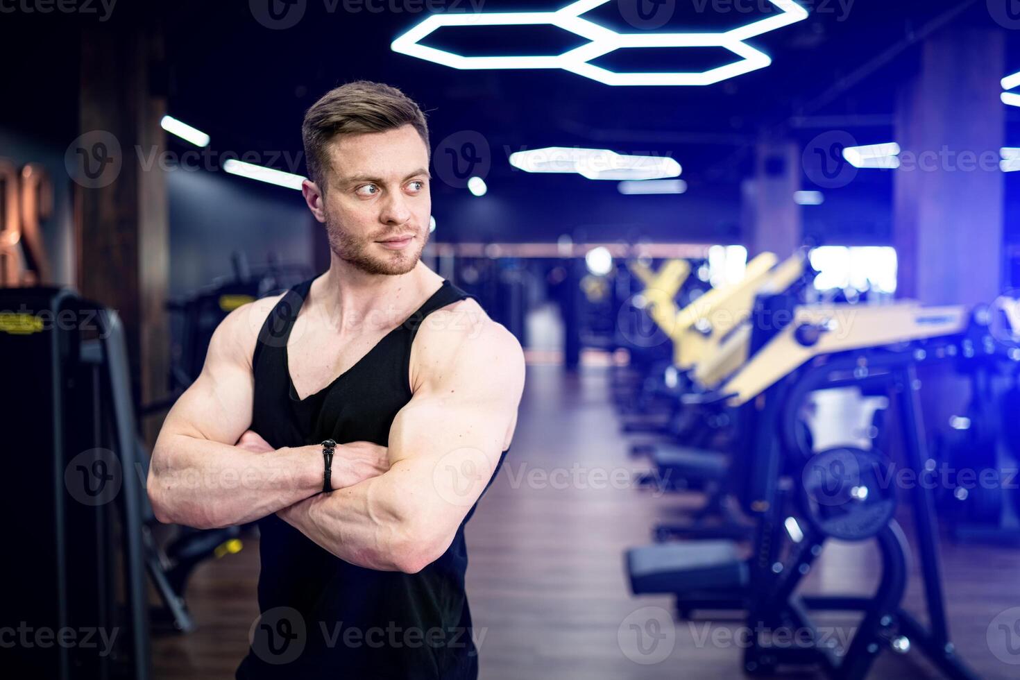 hombre con atlético cuerpo en pie en el gimnasia. confidente muscular entrenador en el gimnasia. foto