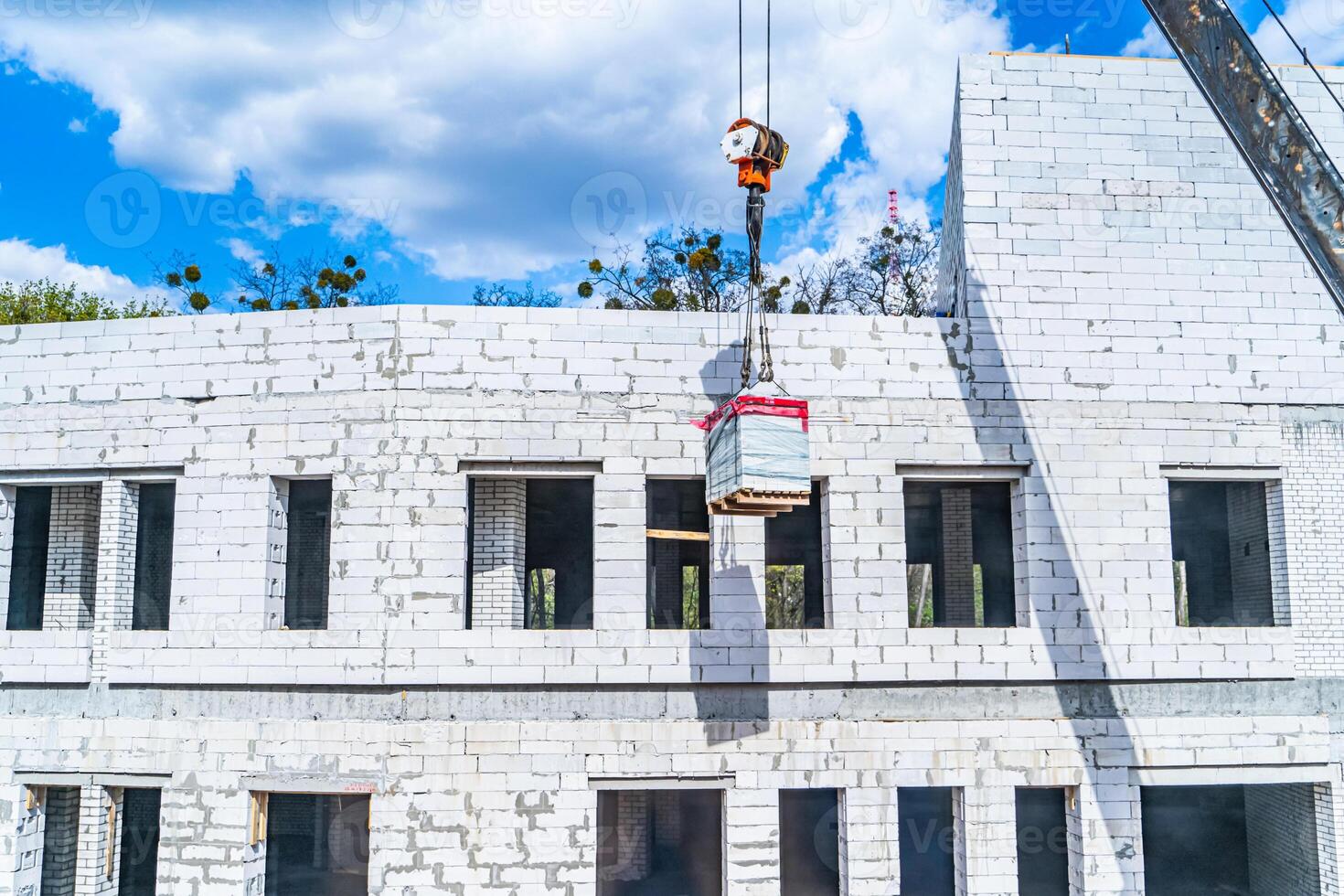 Construction crane in front of a multi storey building under construction lined with bricks. photo