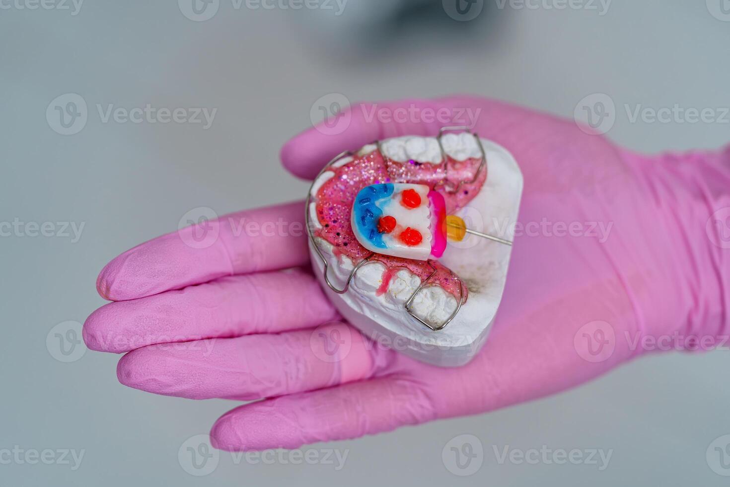 Teeth model on hand on blurred background. Plastic teeth in one row with visible connectors. Human jaw for dentistry training. photo