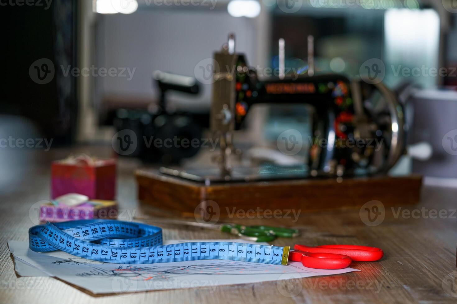 Blue measuring tape and scissors with red handle on sketches with dresses. Tailor s sketches, design work. Draft with beautiful dresses on table. Tailor concept. Close-up. photo