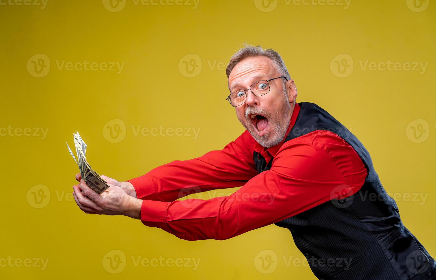 Businessman and money. Straching against dollars. Man holding lots of dollar bills in hands, isolated on yellow background. Rich with success. Positive emotion facial expression feelings. photo