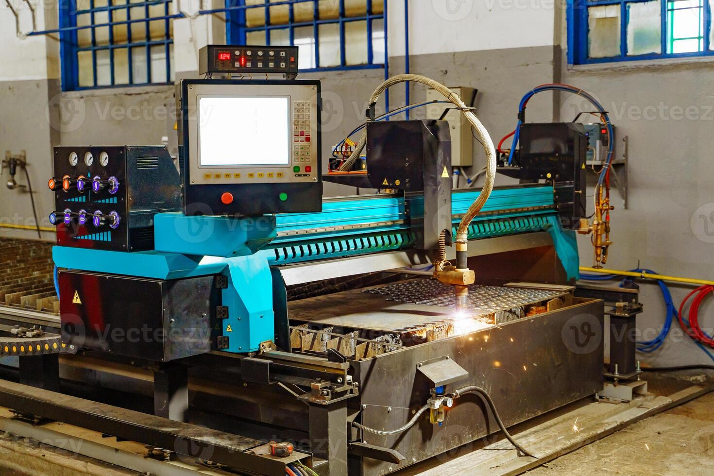 Metallurgical laser machine works to cutting metal indoor in the factory. Industrial equipment for cutting metal in process with sparkling light. photo