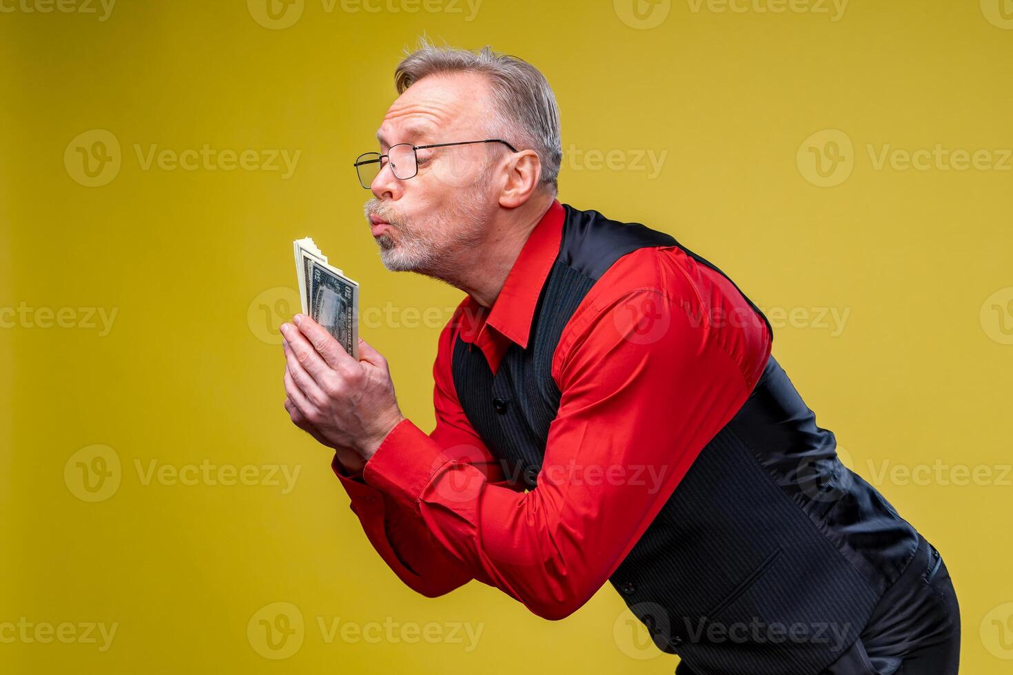 Man holding lots of dollar bills in hands, isolated on yellow background. Happy man enjoying money. Hands with money. Rich with success. Positive emotion facial expression feelings. photo