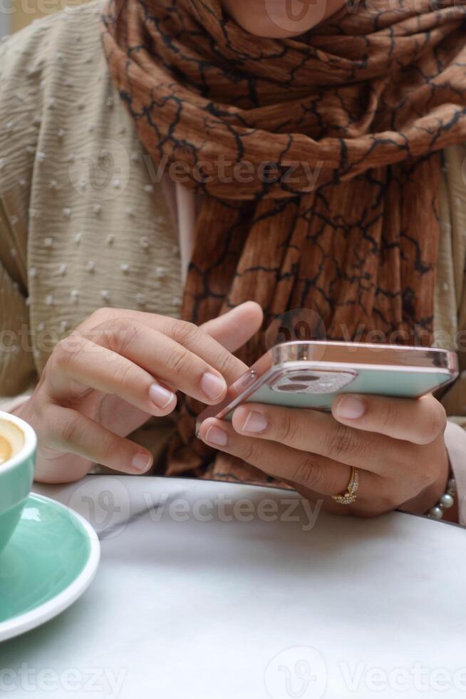 women hand holding smart phone sitting on cafe photo