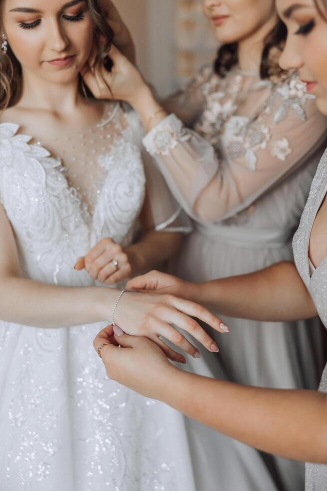 Wedding bride and bridesmaid help with jewellery bracelet for elegant and classic fashion glamour. Expensive bridal diamond accessory for classy style at special ceremony event day closeup. photo