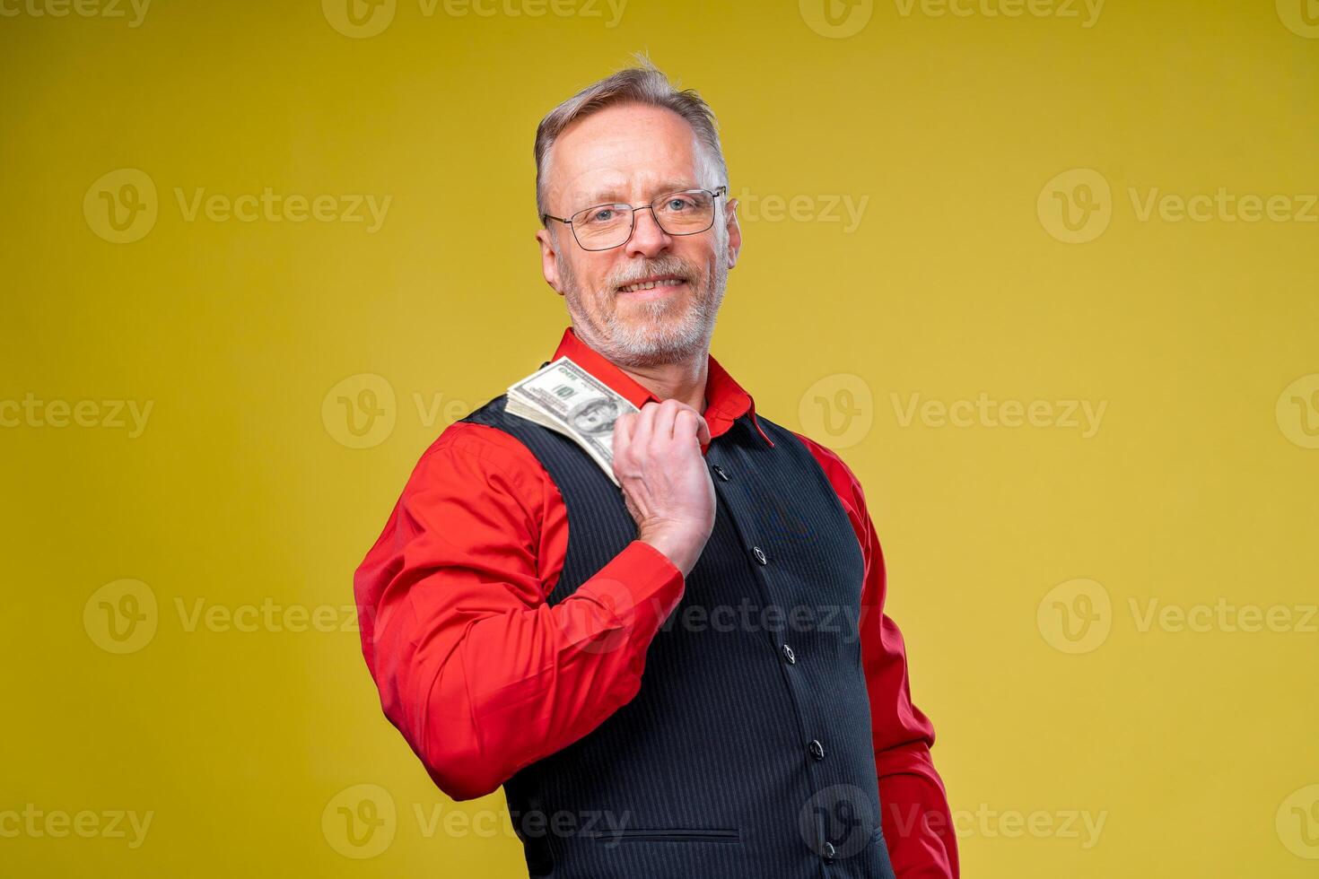 Happy eldery business man with fan of dollar bills isolated on yellow background. Senior man guy won the lottery. Lucky day. Human emotions and facial expressions photo