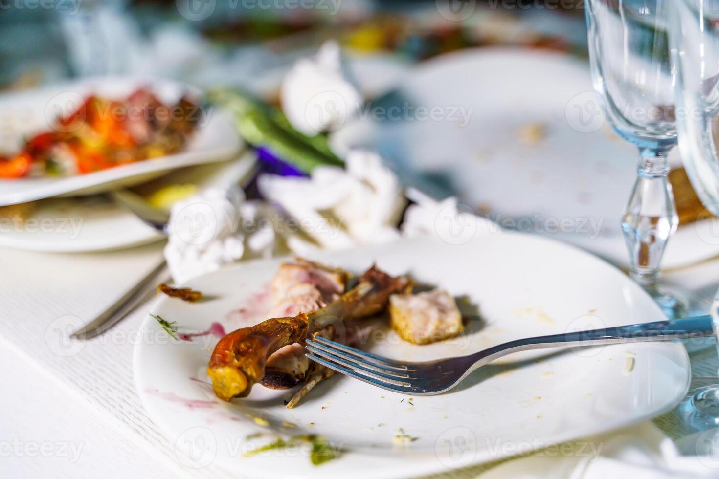 The leftover food and dirty dishes on the restaurant table. Scraps left over after the party. photo