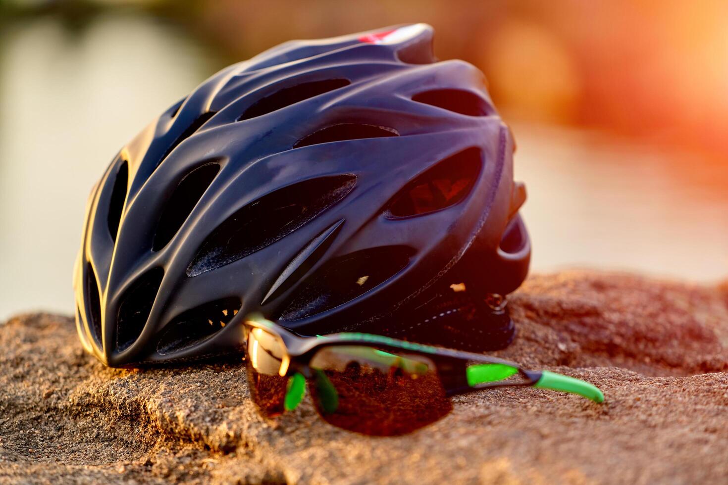 Bicycle helmet and bike glasses on the street, rock with blurred background. photo