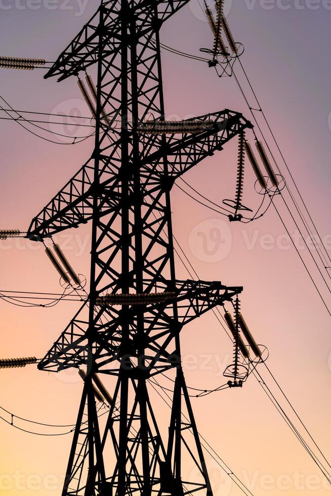 Electricity pylon on the background of sky. Big iron structure of high voltage. Selective focus from below. photo