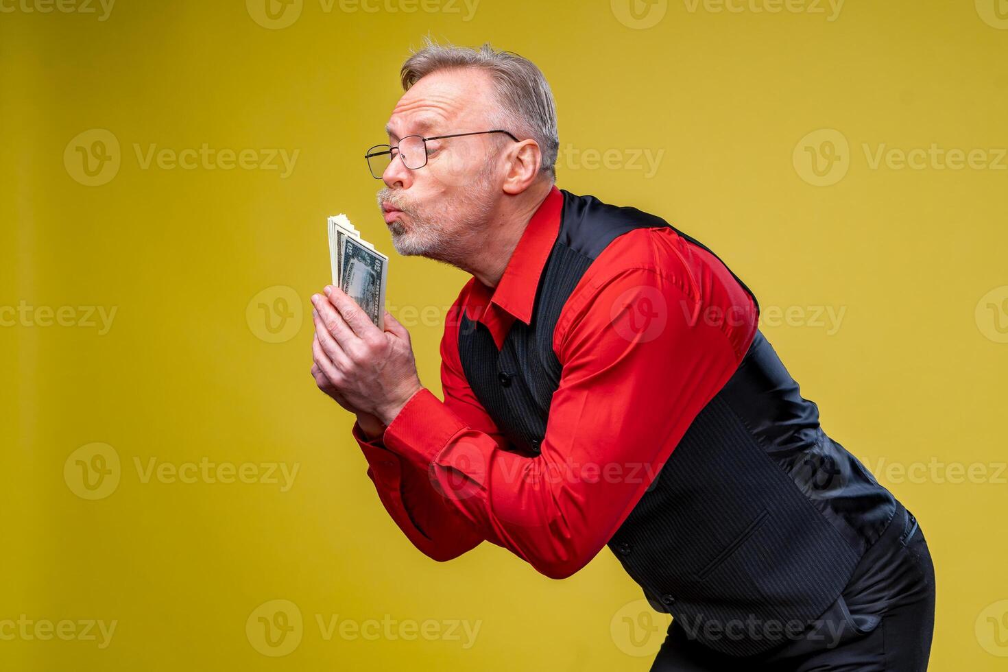 Man holding lots of dollar bills in hands, isolated on yellow background. Happy man enjoying money. Hands with money. Rich with success. Positive emotion facial expression feelings. photo