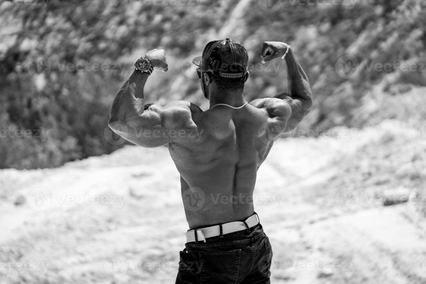 Athletic man with strong back showing power. Handsome bodybuilder with naked torso posing. photo