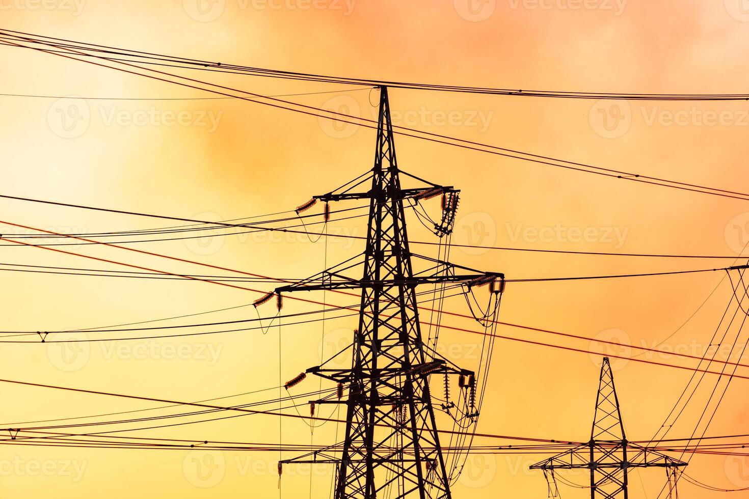 Dark silhouette of electric tower on red sky background. Transmission lines of high-voltage electric towers at sunset photo