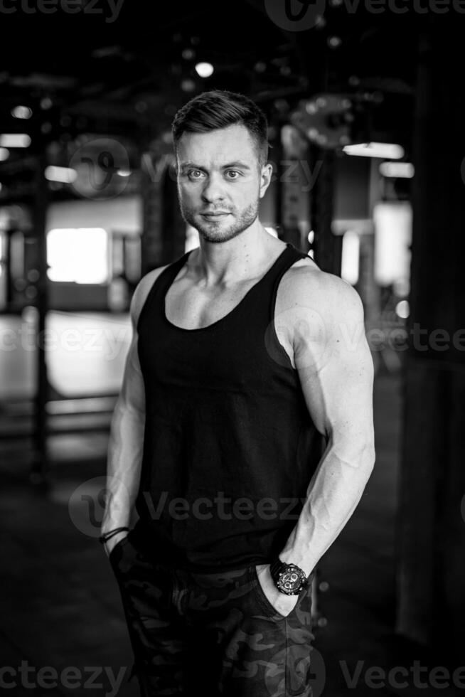 hermoso fuerte hombre posando a el gimnasia. atlético joven masculino modelo con fuerte manos. foto