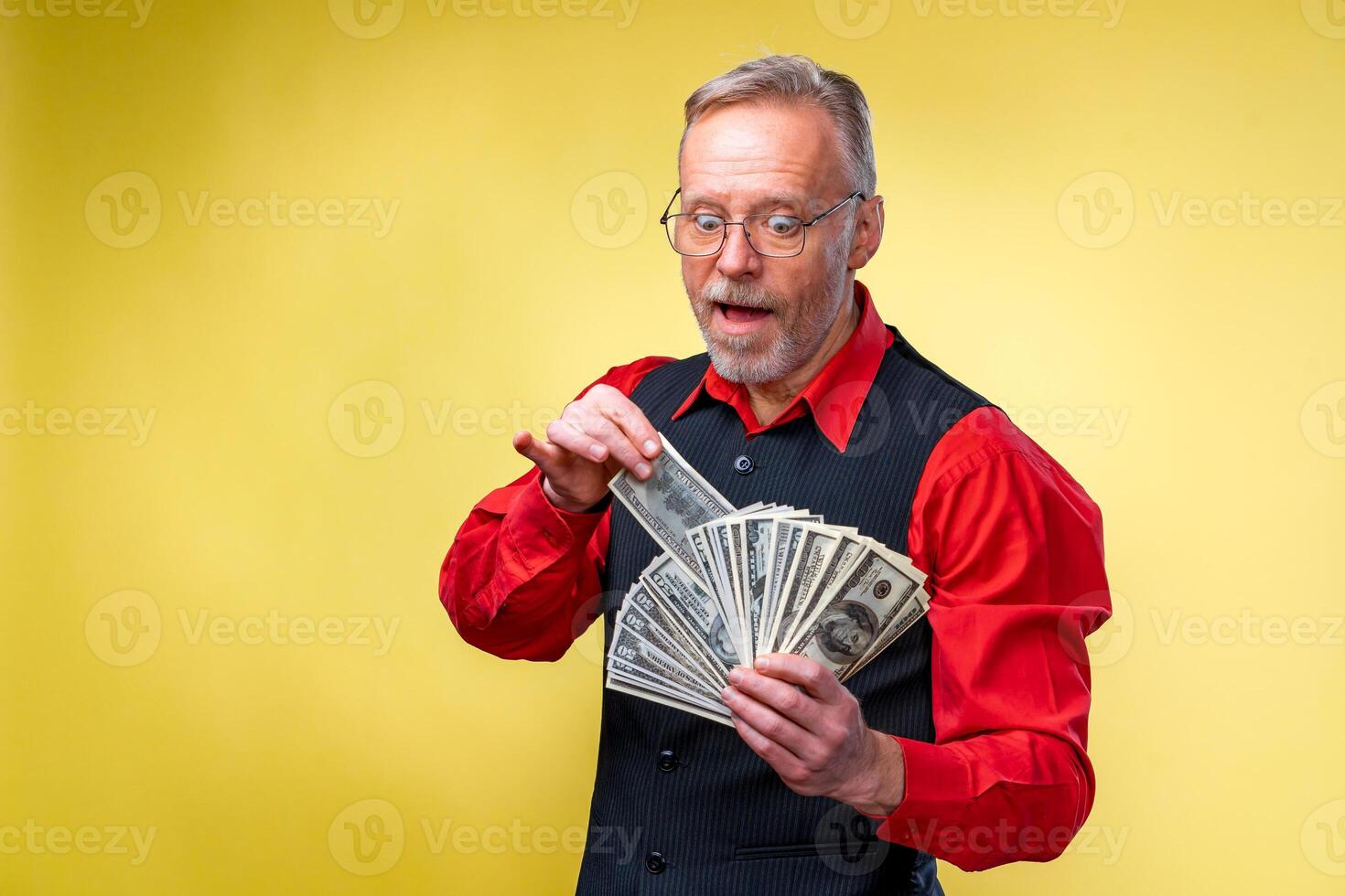 Happy eldery business man with fan of dollar bills isolated on yellow background. seniour man guy won the lottery, Lucky day. Human emotions and facial expressions photo