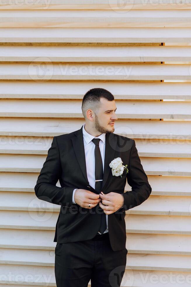 Portrait of a handsome young groom on an autumn day outdoors in an elegant suit. Outdoor photo. Handsome man in a business suit. photo