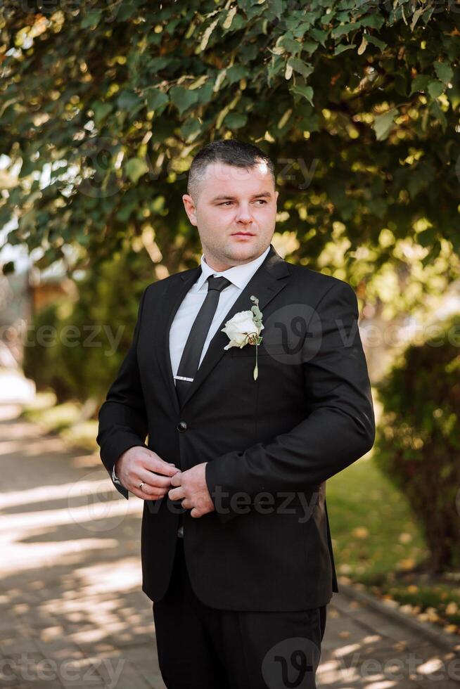 Portrait of a handsome young groom on an autumn day outdoors in an elegant suit. Outdoor photo. Handsome man in a business suit. photo