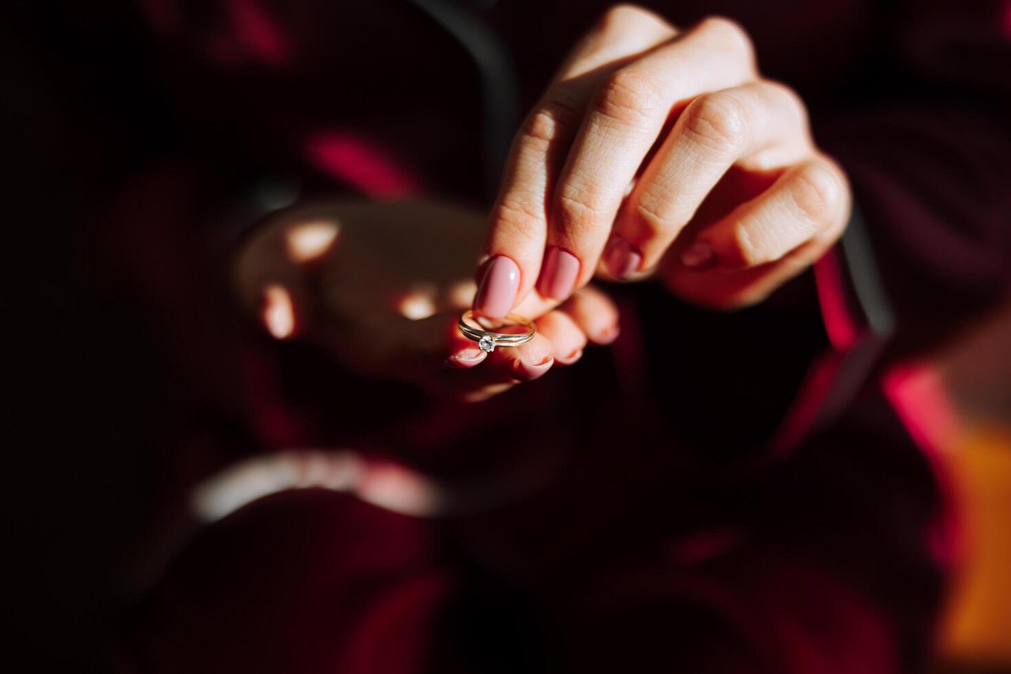 Morning of luxurious and beautiful bride in hotel in luxurious room in red pajamas with gold ring on finger close-up. photo